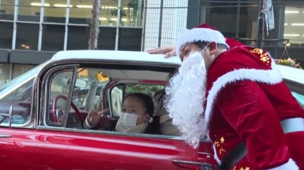 東京・丸の内で、クラシックカーに乗るサンタが子供たちにプレゼント