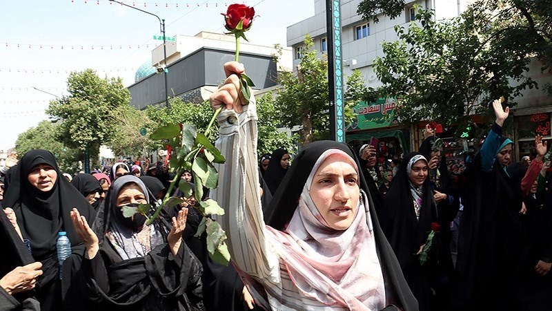 Seorang warga Iran membawa bunga dan berjalan menuju Kompleks Haram Suci Imam Ridha as, Minggu (21/5/2023).