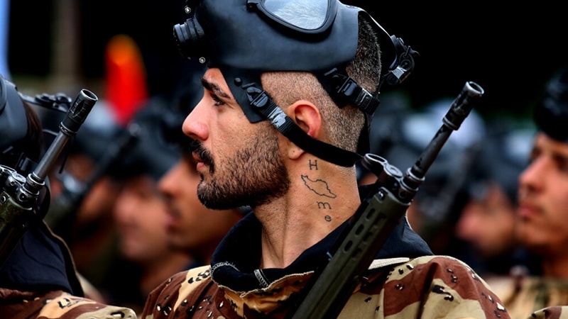 An Army soldier with a tattoo on his neck showing the word home and the Iranian flag